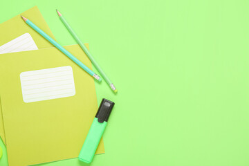 Notebooks with marker and pencils on green background