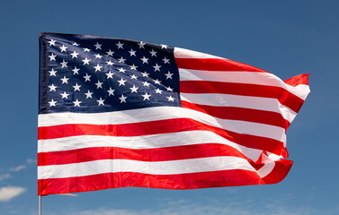 Fototapeta premium Large USA flag flying against clear blue sky and clouds