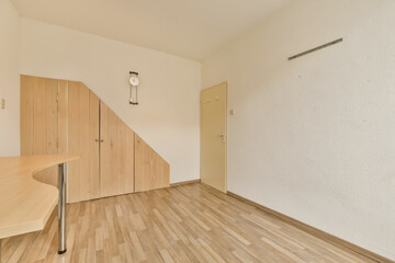 an empty room with wooden floors and white walls, there is a clock on the wall in front of the door