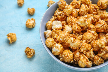 Bowl with tasty popcorn on blue background