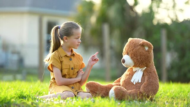 Unhappy teenage girl having an argument shaking her finger on her teddy bear friend. Concept of friendship difficulties