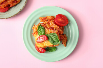 Plate of pasta with tomato sauce and cheese on pink background