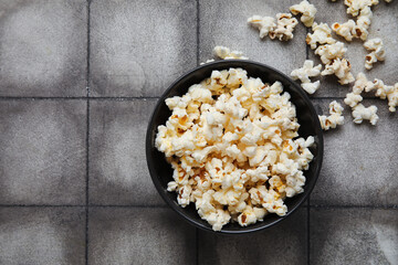 Bowl with tasty popcorn on grey tile background