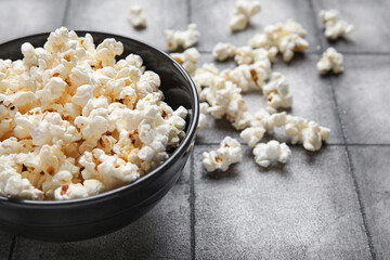 Bowl with tasty popcorn on grey tile background