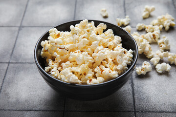 Bowl with tasty popcorn on grey tile background