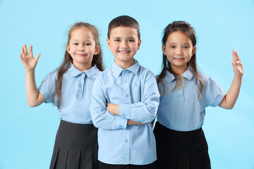 Little schoolchildren on light blue background