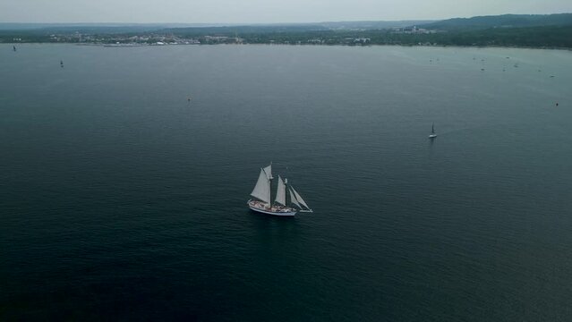 Aerial footage of a schooner on West Grand Traverse Bay in Lake Michigan Tall ship at sea, majestic vessel sailing on serene bay waters.
