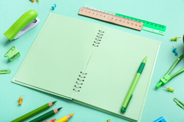 Blank notebook and different stationery on turquoise background
