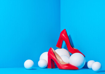 Pair of bold red pointed-toe high heels located in bright blue three-dimentional background. Copy space. Mock up for design advertising for shoe store