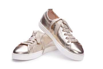 Close up view of trendy female casual metallic gold sneakers with thick shoelaces and white sole...