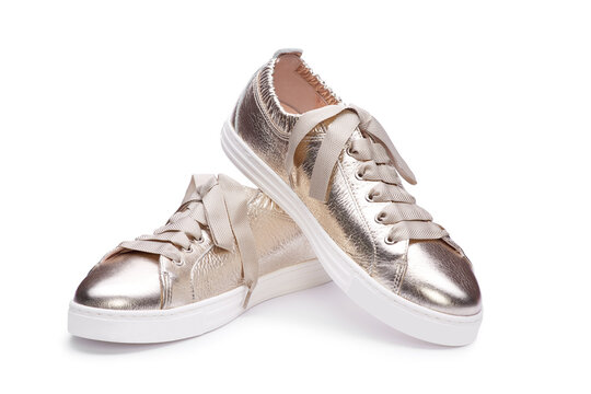 Close up view of trendy female casual metallic gold sneakers with thick shoelaces and white sole isolated on white background.  A modern and fashionable shoe store.