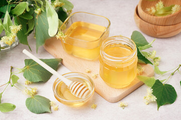 Glass bowls and jar with linden honey on white background