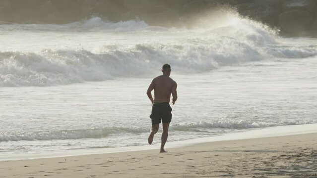 A man jogging on the beach at early sunset