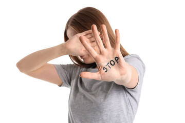 Young woman with word STOP written on her palm against white background