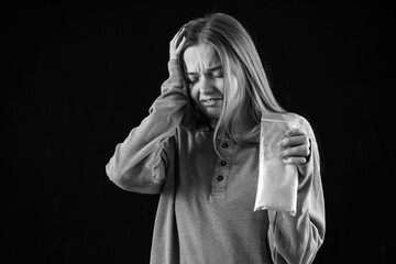 Young female junkie with drugs on black background