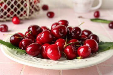 Plate with sweet cherries on pink tile table