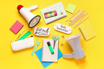 Stationery, megaphone, sheets with text HELLO SEPTEMBER and FIRST DAY OF SCHOOL on yellow background