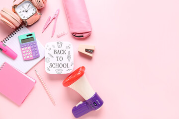 Headphones, alarm clock, megaphone and sheet with text BACK TO SCHOOL on pink background