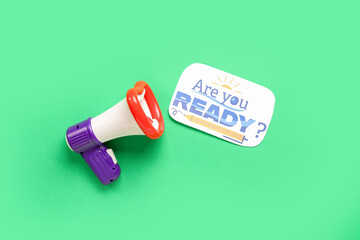 Megaphone and sheet with question ARE YOU READY? on green background