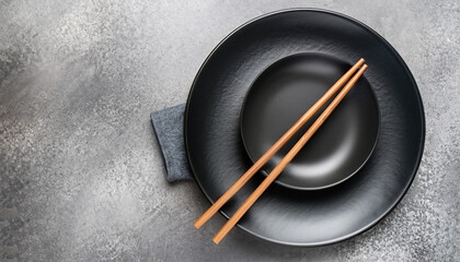 Set of dark plates and chopsticks on stone background. Set for Asian, Japanese and Chinese food....