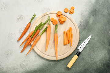 Wooden board with fresh carrots and slices on white background