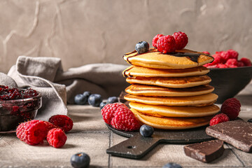Board of tasty pancakes with raspberries and blueberries on table