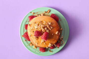 Plate of tasty pancakes with raspberries on lilac background