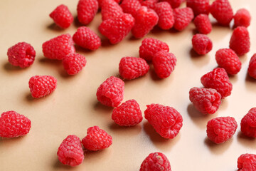 Many fresh raspberries on beige background