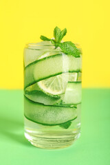 Glass of fresh cucumber mojito on color background
