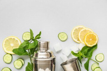 Cocktail shaker and jigger with mojito ingredients on light background