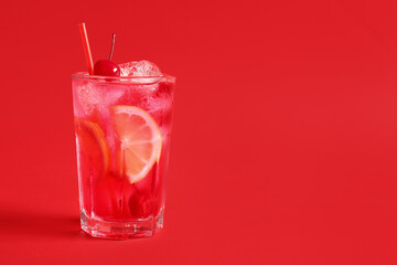 Glass of tasty cocktail with maraschino cherry on red background