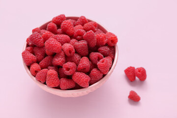 Bowl with fresh raspberry on pink background, closeup