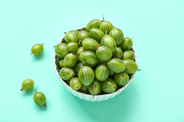 Bowl with fresh green gooseberry on turquoise background, closeup