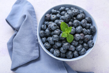 Bowl with fresh blueberry on light background, closeup