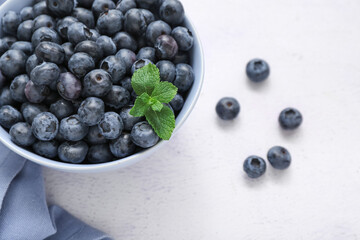 Bowl with fresh blueberry on light background, closeup