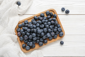 Board with fresh blueberry on light wooden background