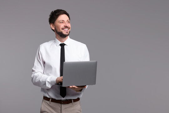 Happy man with laptop on grey background. Space for text