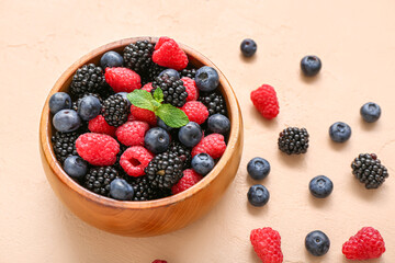 Bowl with different fresh berries on beige background, closeup