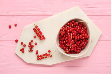 Bowl with fresh red currant on pink wooden background