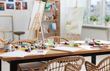 Artist's studio with different painting supplies on table. Creative hobby
