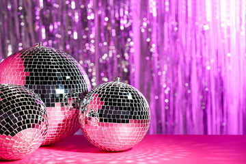 Many shiny disco balls on table against blurred background, toned in pink. Space for text