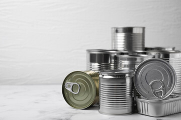 Many closed tin cans on white marble table. Space for text