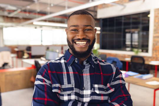 Portrait of happy african american businessman crossing arms and smiling at office