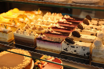 Different delicious cakes on counter in bakery shop, closeup