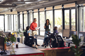 Diverse business people having meeting, discussing work and using laptop and tablet at office