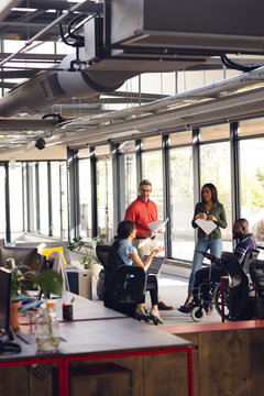Diverse business people having meeting, discussing work and using laptop and tablet at office