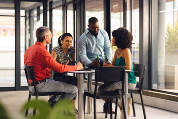 Happy diverse casual business colleagues talking and drinking beers in office
