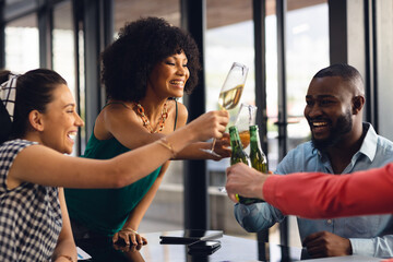 Happy diverse business colleagues drinking beer and champagne, making a toast in office