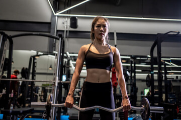 Portrait of a young Asian woman, good-looking, shapely, in a black dress. She's working exercise...