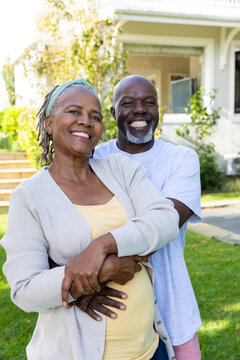 Portrait of happy senior african american couple smiling and embracing in sunny garden